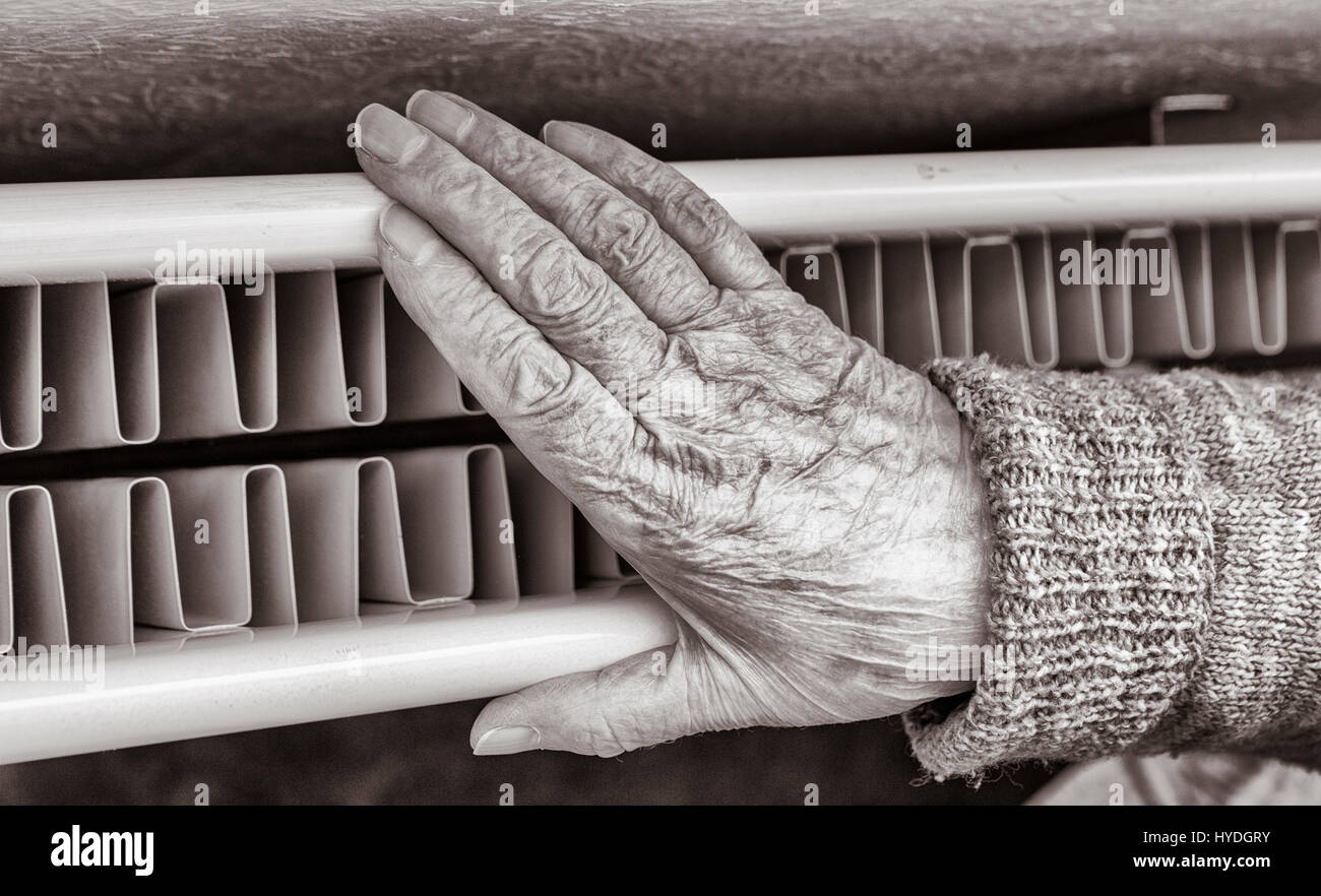 90 ans, femme, et avec la main sur le radiateur. UK Banque D'Images