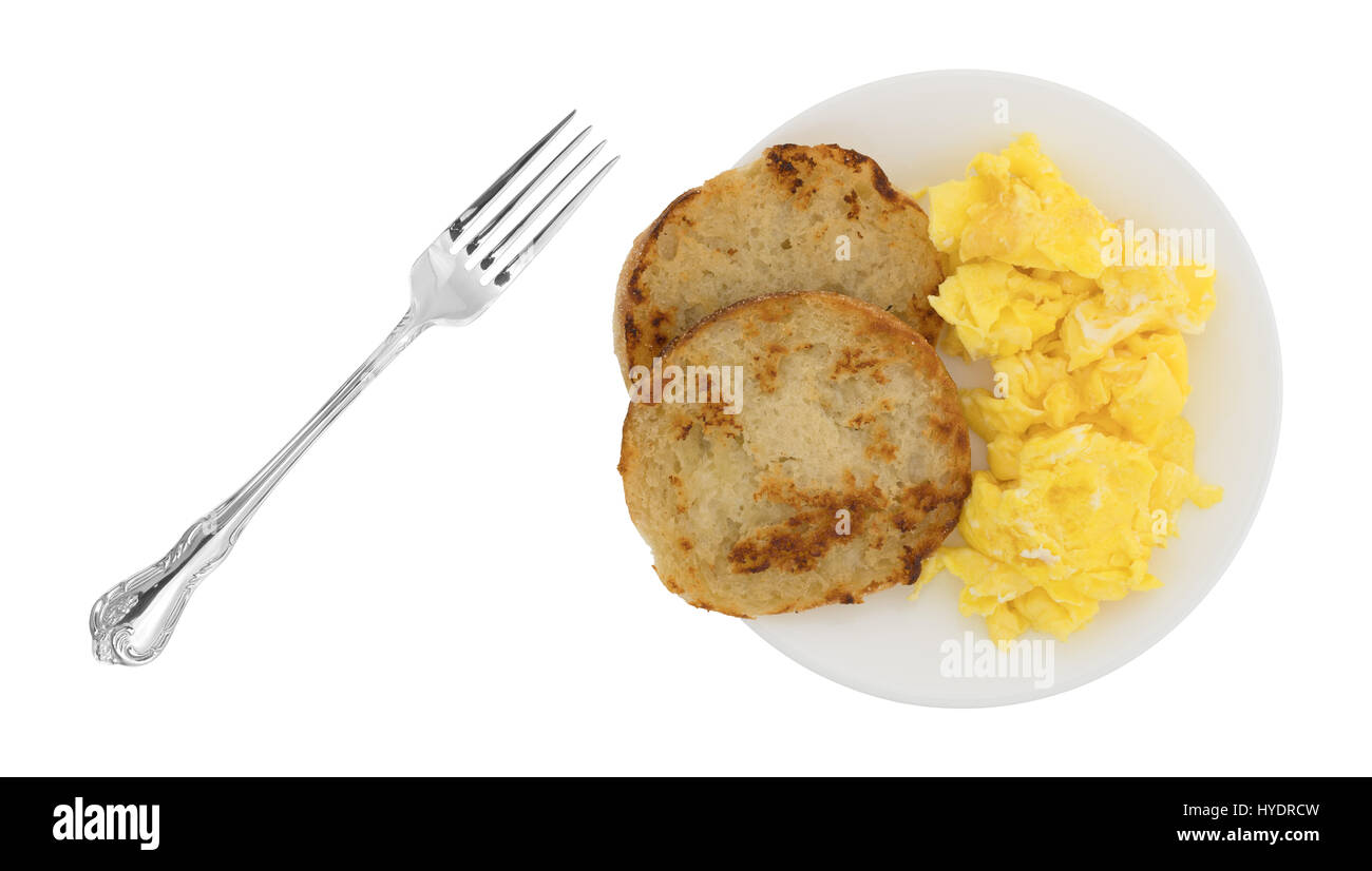 Vue de dessus d'un frites fraîchement muffin anglais avec œufs brouillés sur une assiette et une fourchette pour le côté isolé sur un fond blanc. Banque D'Images