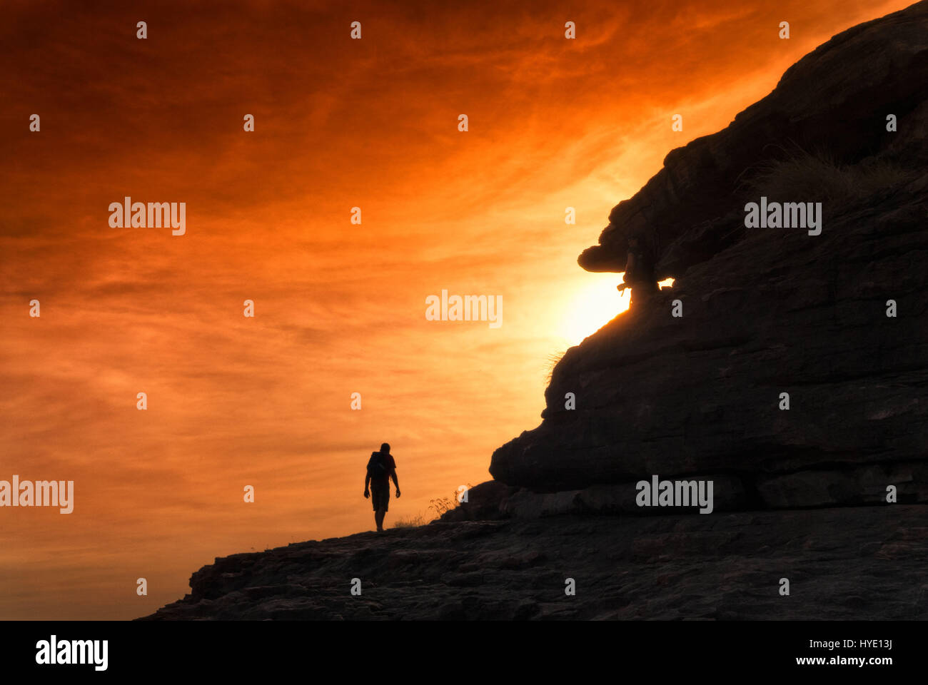 Silhouette de randonneur en montant au coucher du soleil avec ciel rougeoyant orange. Territoires du Nord, Australie Banque D'Images