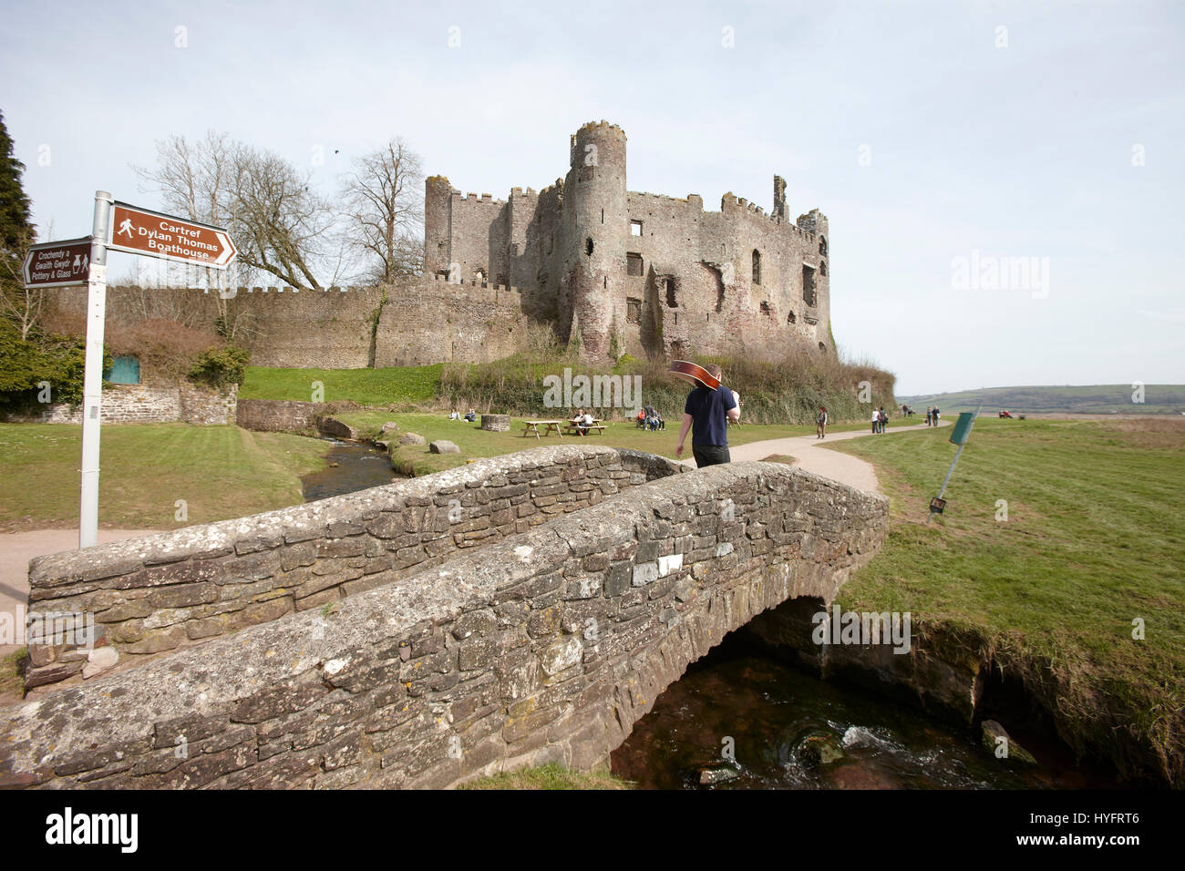 Un homme qui marche avec une guitare en main sur un pont par Laugharne Castle,le festival littéraire, Carmarthen, pays de Galles, Royaume-Uni Banque D'Images