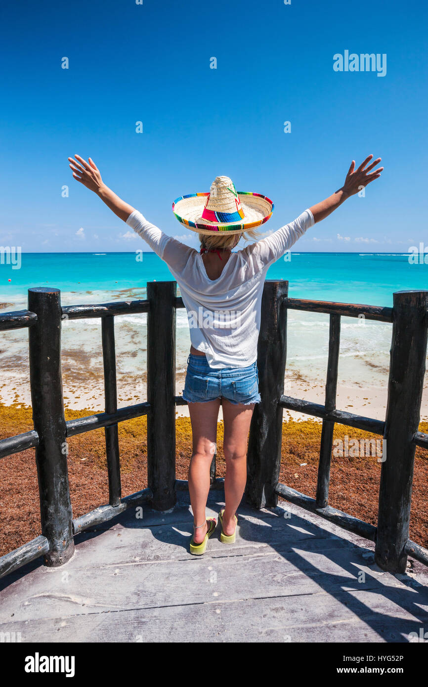 Vue arrière du ypoung portrait femme debout sur la plage avec le sien mains wide open à Tulum, Mexique Banque D'Images