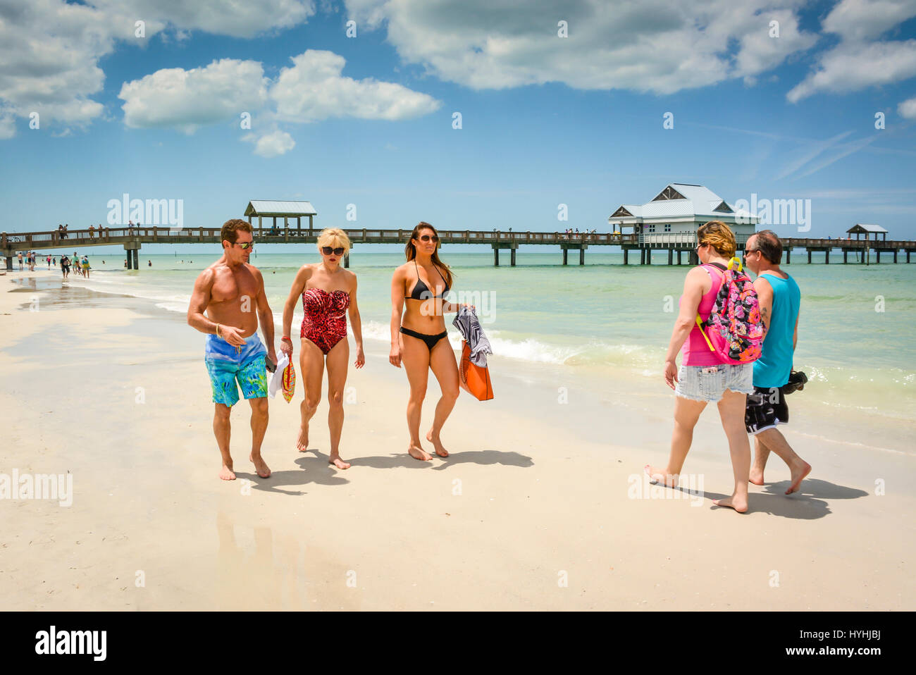 Couples, Familles, amis, vous promener sur la plage de sable blanc de Clearwater Beach, FL le long du rivage avec Pier 60 en arrière-plan dans la vie en plein air actif Banque D'Images