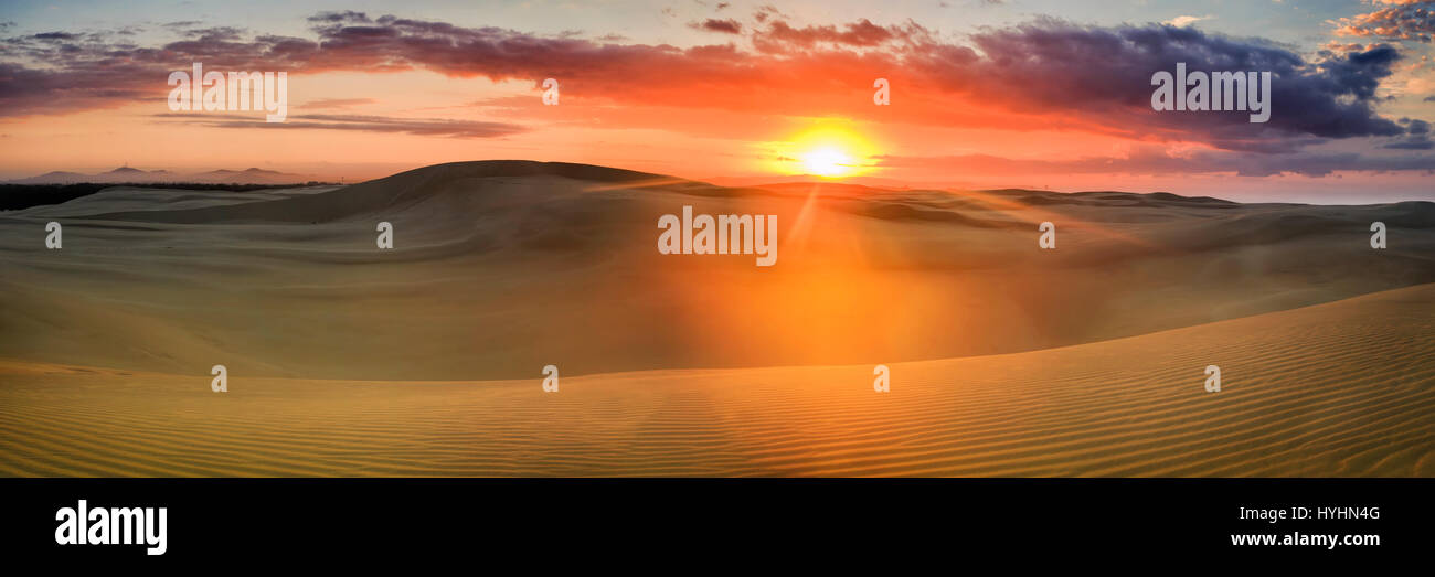 Large panorama de dunes de sable désertes à colorful sunrise over horizon lointain. Dessins de sable vierge éclairée par les rayons de lumière. Banque D'Images
