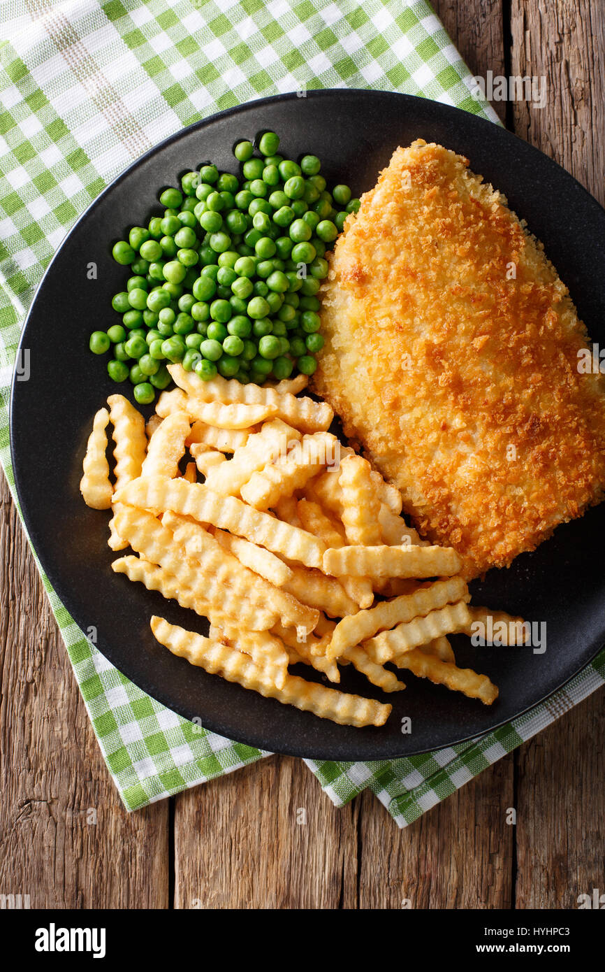 Fish and chips avec les pois verts close-up sur une plaque sur une table. Vue verticale d'en haut Banque D'Images