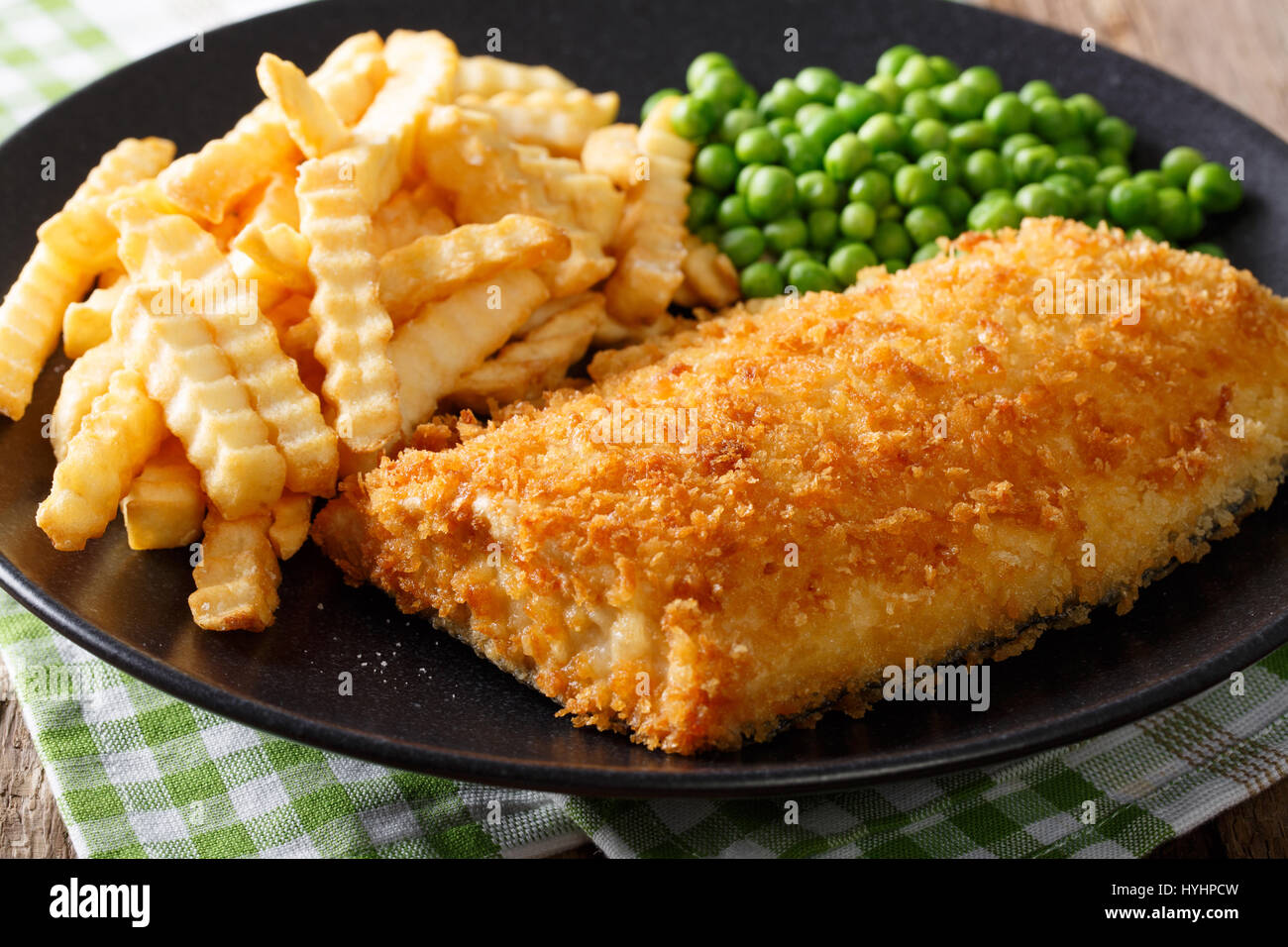 La cuisine britannique traditionnelle : fish and chips avec les pois verts close-up sur une plaque sur une table horizontale. Banque D'Images