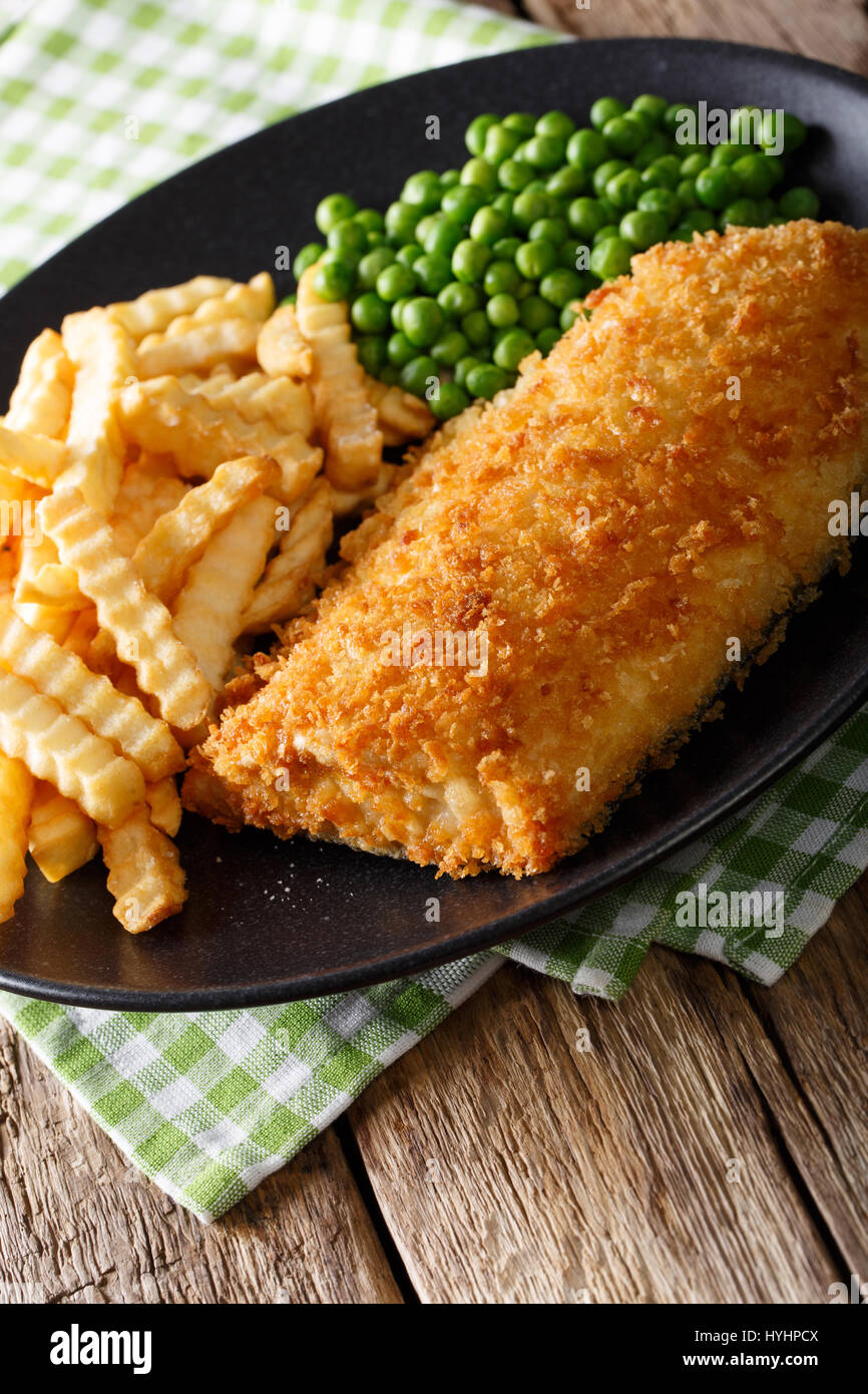 La cuisine anglaise : fish and chips avec les pois verts close-up sur une plaque sur une table verticale. Banque D'Images