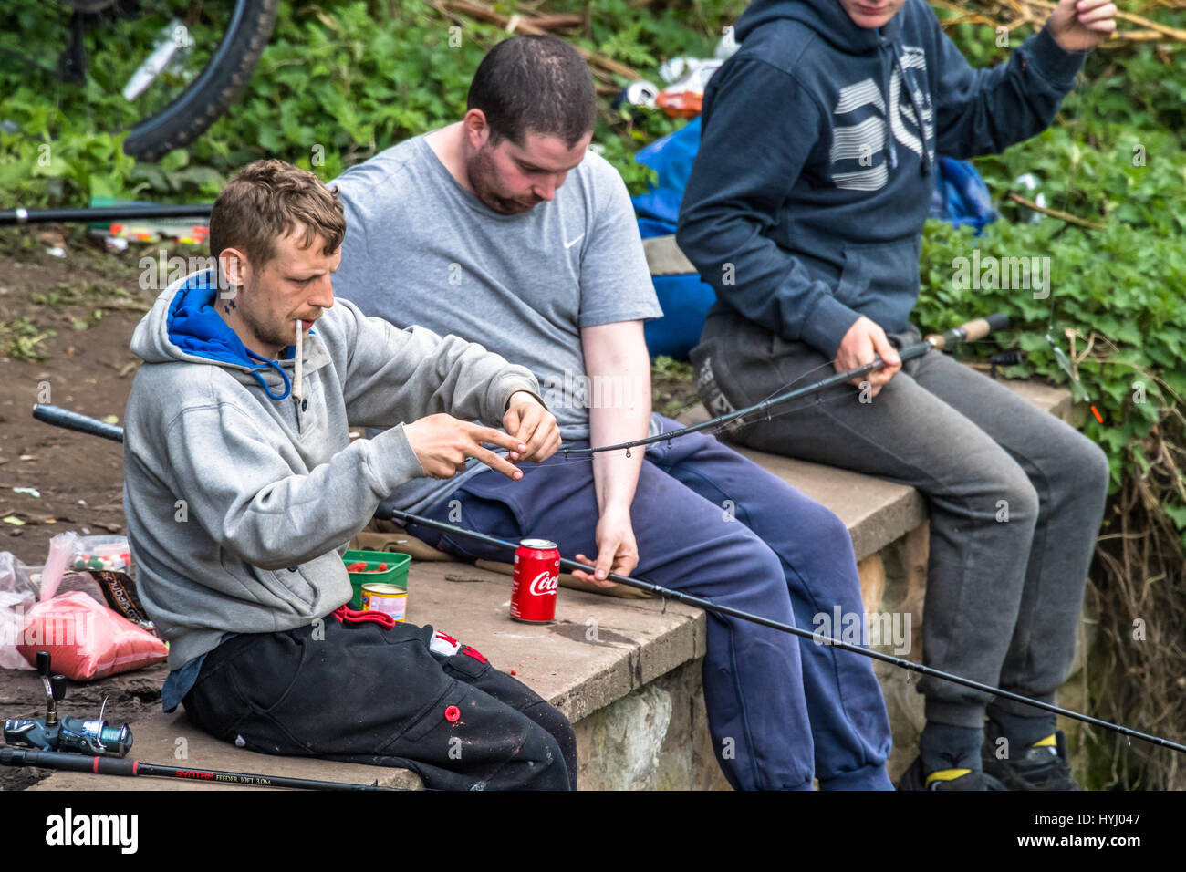 Trois hommes la pêche sur une rivière tandis que l'un fume un joint. Banque D'Images