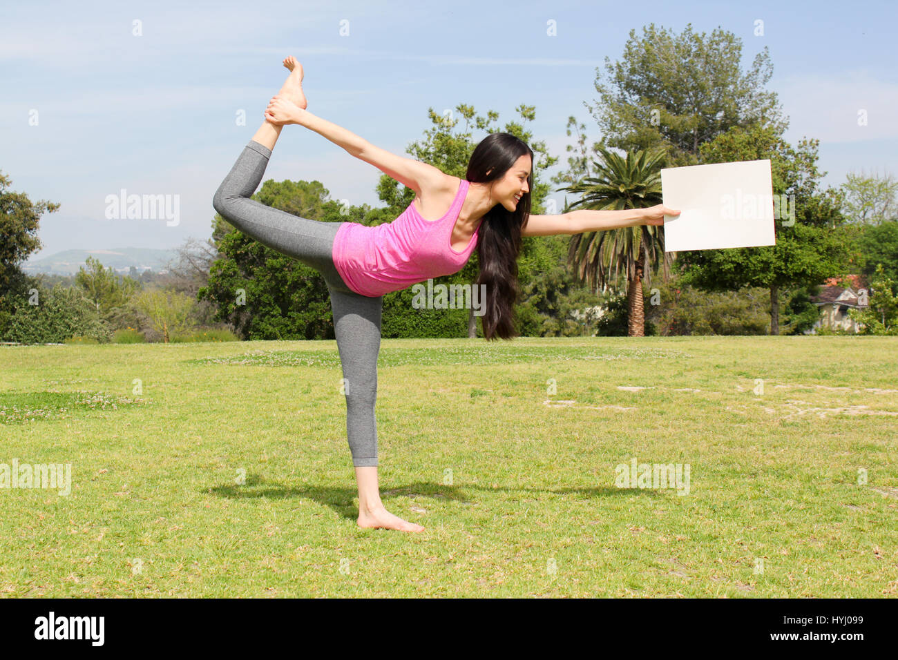 Belle femme faisant du yoga à l'extérieur tenant une feuille de papier vierge. Banque D'Images