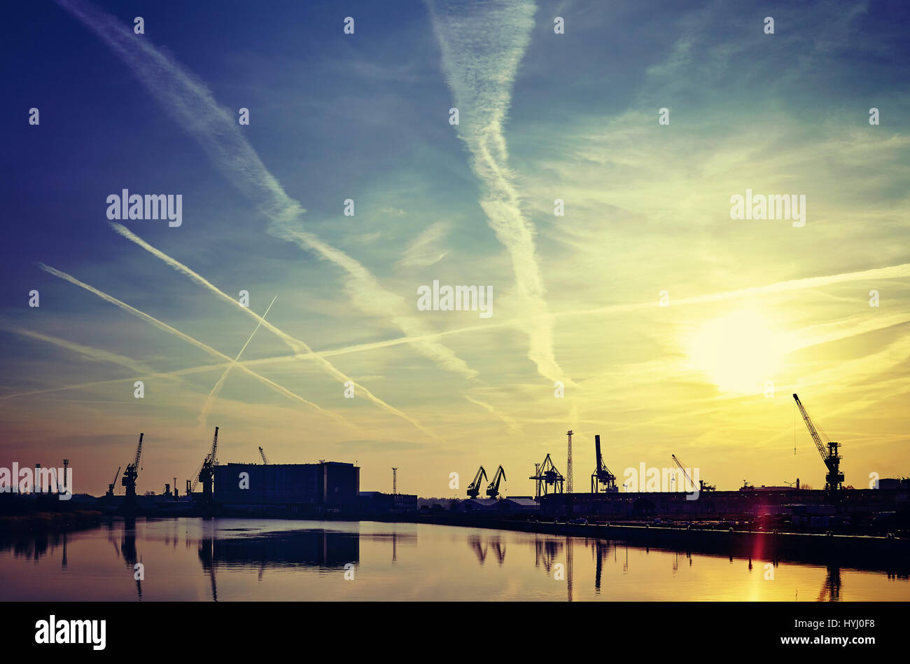 Lever du soleil sur les grues portuaires silhouettes avec ciel dramatique, harmonisation des couleurs appliquées. Banque D'Images