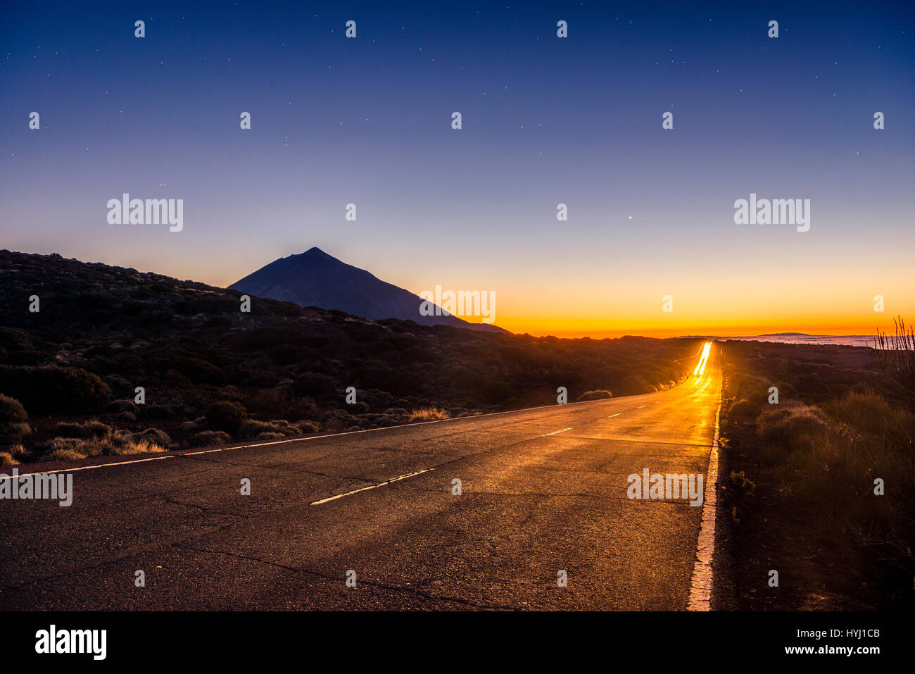 Des sentiers de lumière à partir de la voiture sur route de montagne, la route, coucher de soleil, Vulcano rétroéclairé Teide, silhouette, paysage volcanique, ciel étoilé Banque D'Images