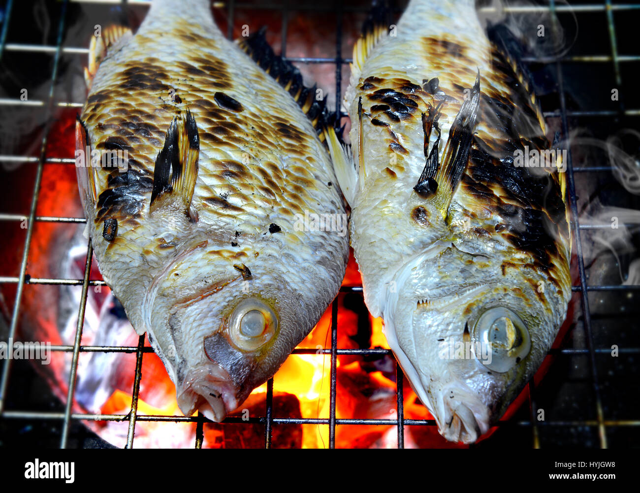 Grill poissons sur le charbon de la cuisson dans l'éclairage photo flash. Banque D'Images