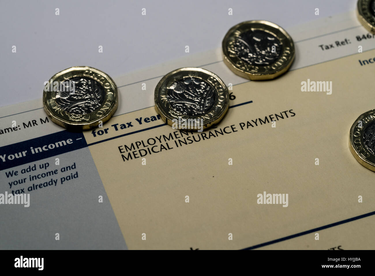 Déclaration de revenus personnels montrant les chiffres de l'impôt sur le revenu et d'impôt britannique couverts par quelques nouvelles pièces livre un Banque D'Images