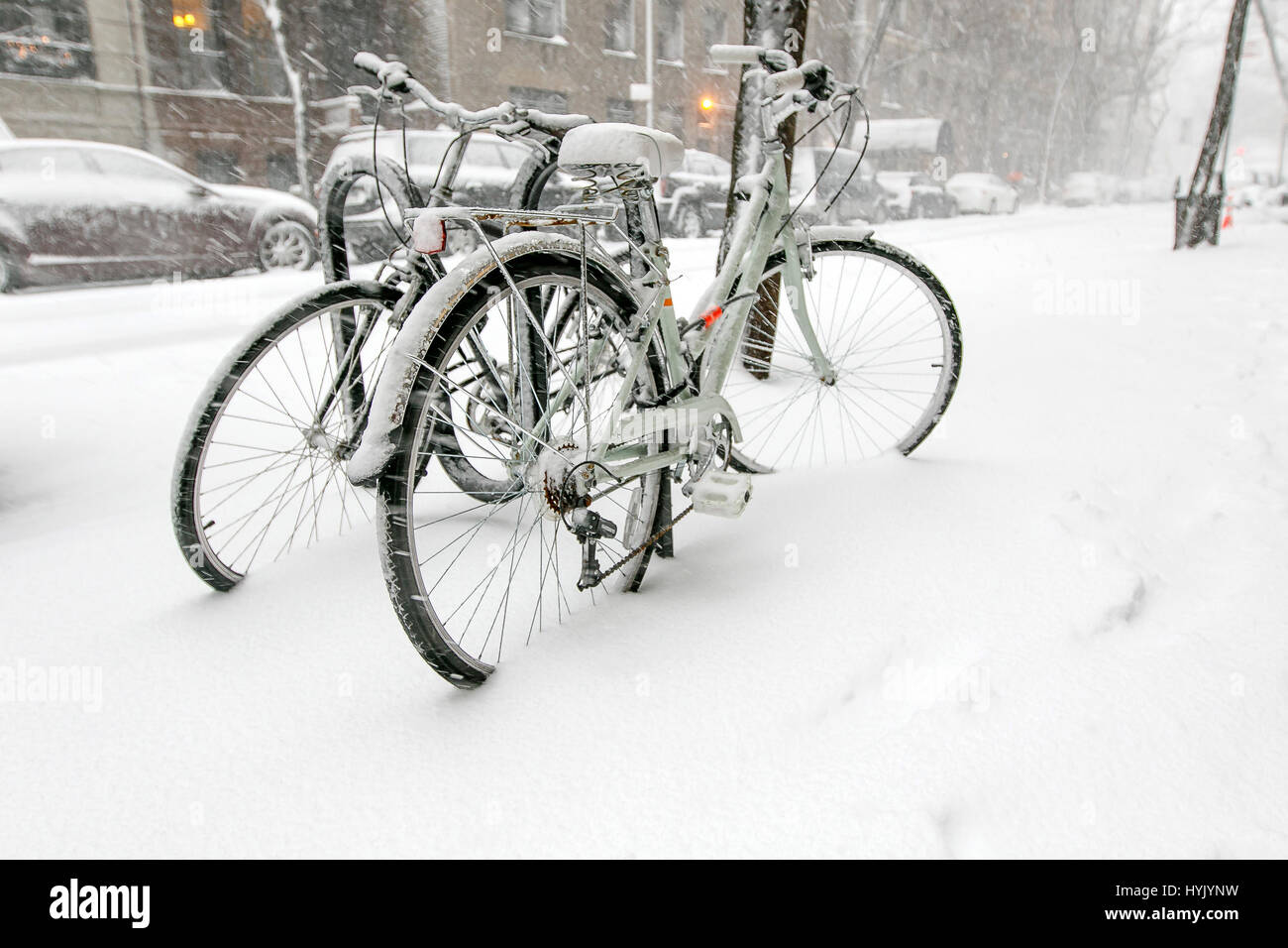 Deux bicyles enchaînés à un rack à l'extérieur sont couvertes de neige pendant une chute de neige à Manhattan. Banque D'Images