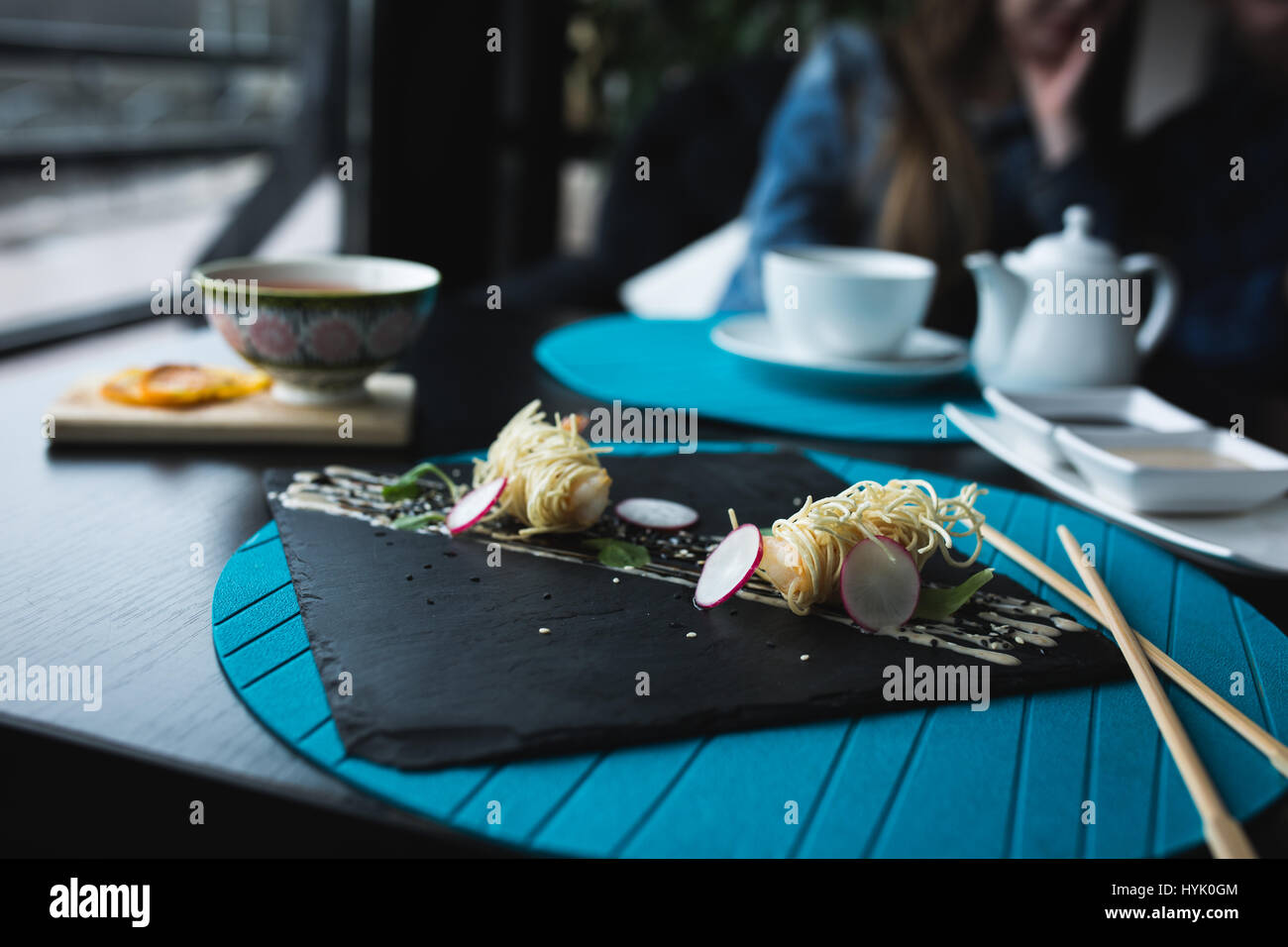 Crevettes Tiger en nouilles chinoises avec la sauce sur la plaque noire. Concept d'aliments asiatiques. Les gens sur place dans le restaurant avec table en bois. Copie Flare Banque D'Images