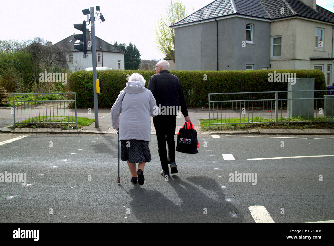 Vieux couple crossing road au feu avec bâton de marche Banque D'Images
