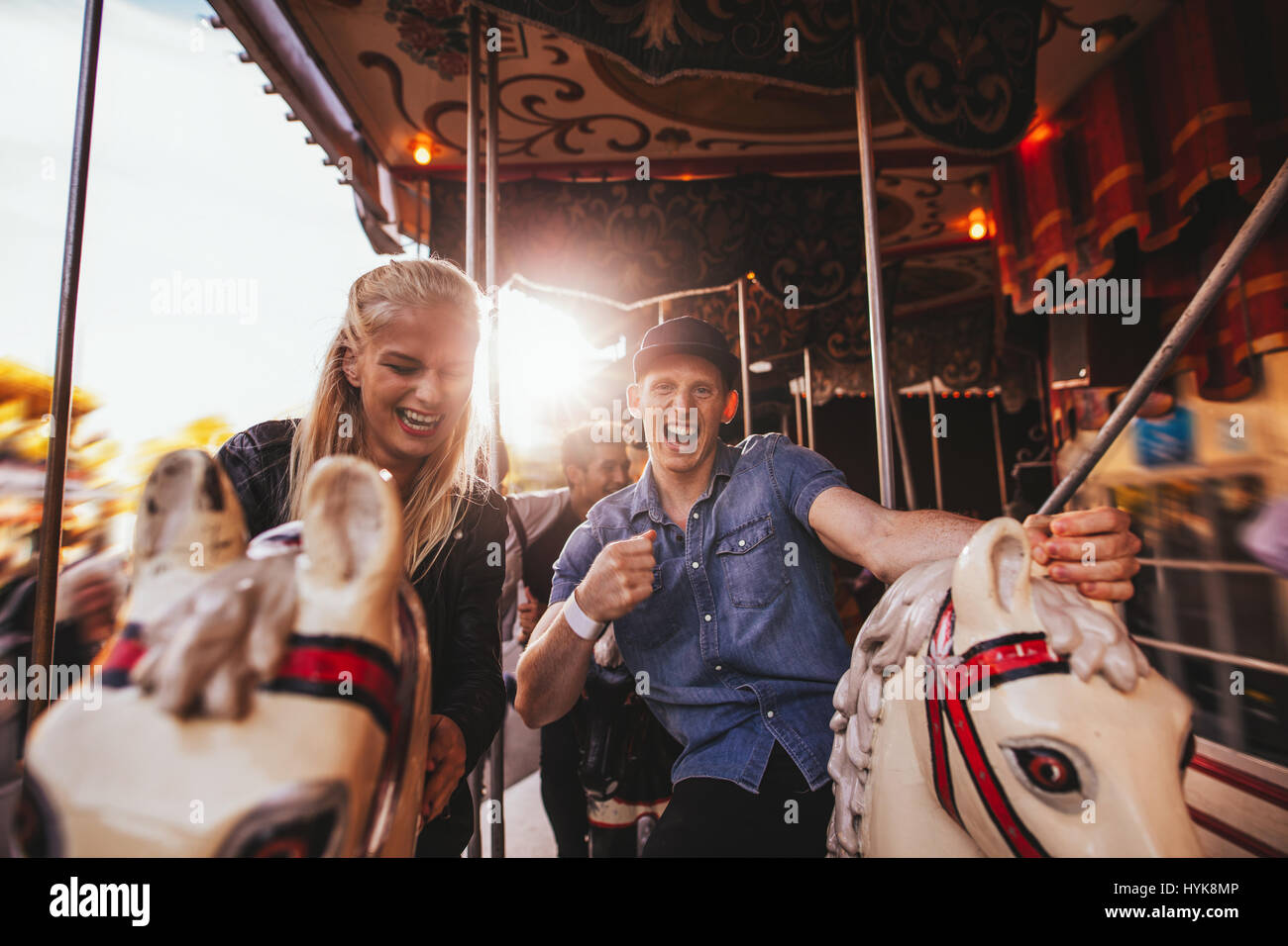 Coup de jeune couple s'amusant dans un parc d'ride. Smiling man and woman on horse carousel ride au parc des expositions. Banque D'Images
