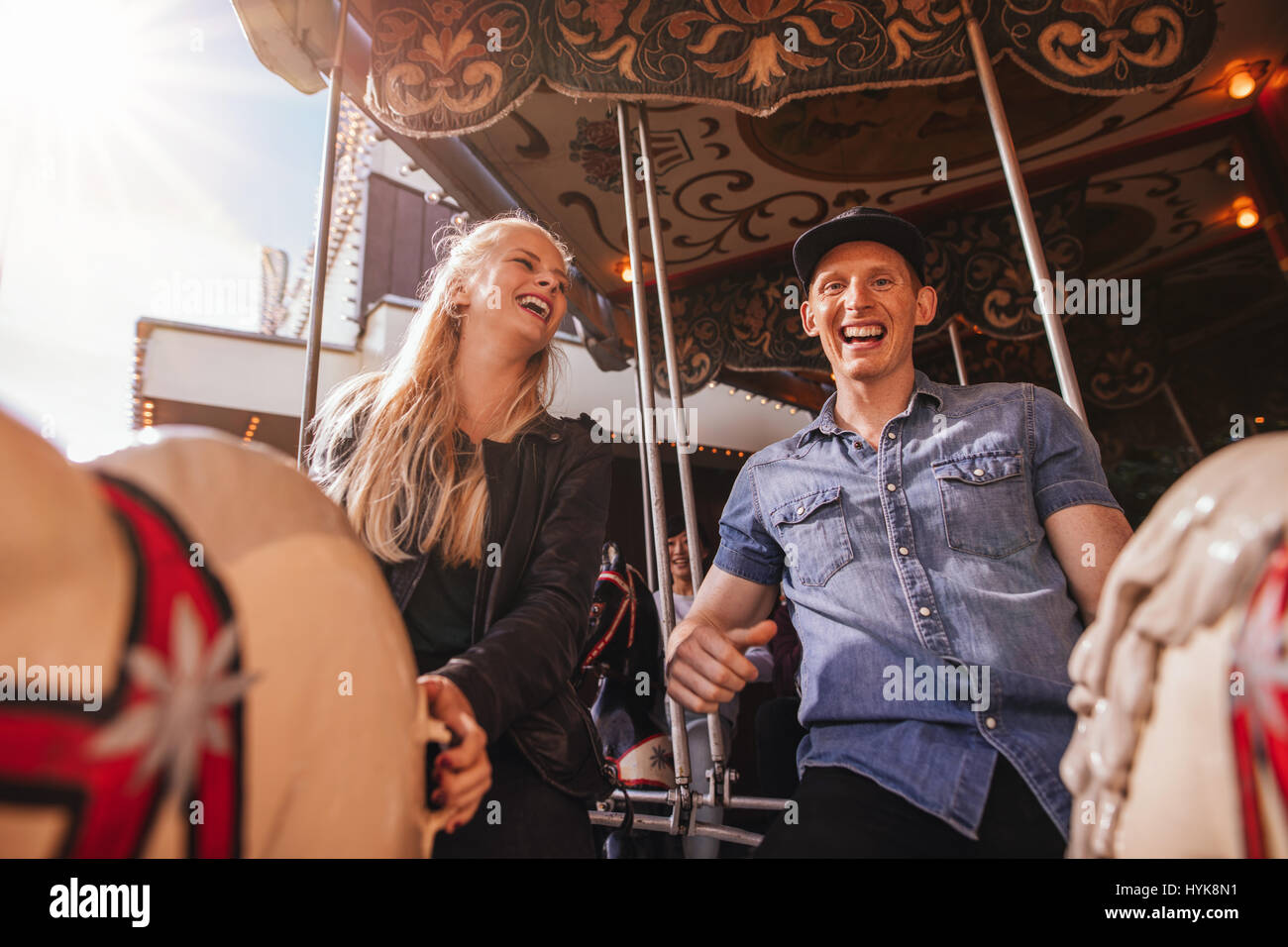 Smiling friends sur amusement park carousel. Jeune couple sur carousel ride. Banque D'Images