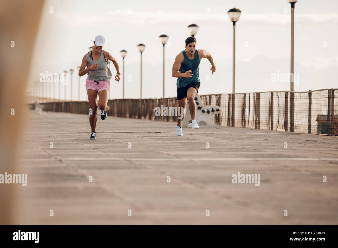 Jeune couple en marche le long d'une promenade en bord de mer. De jeunes coureurs sprint à l'extérieur, le matin. Banque D'Images