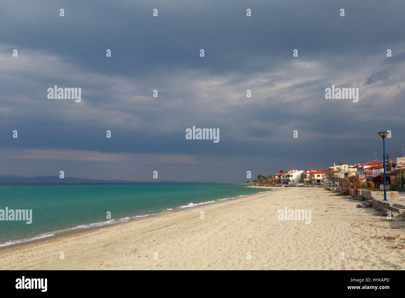 Le village sur le bord de la mer turquoise sous un ciel nuageux sombre avant que la pluie au coucher du soleil de la journée. Kassandra Halkidiki, Grèce Banque D'Images