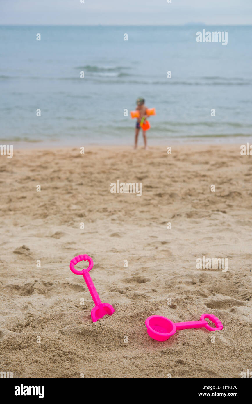 Les jouets pour enfants sur la plage, l'enfant dans l'eau d'arrière-plan Banque D'Images