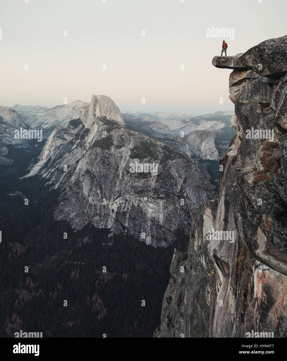 L'intrépide randonneur est debout sur un rocher en surplomb en profitant de la vue vers célèbre Demi Dôme à Glacier Point in Yosemite National Park, Californie Banque D'Images