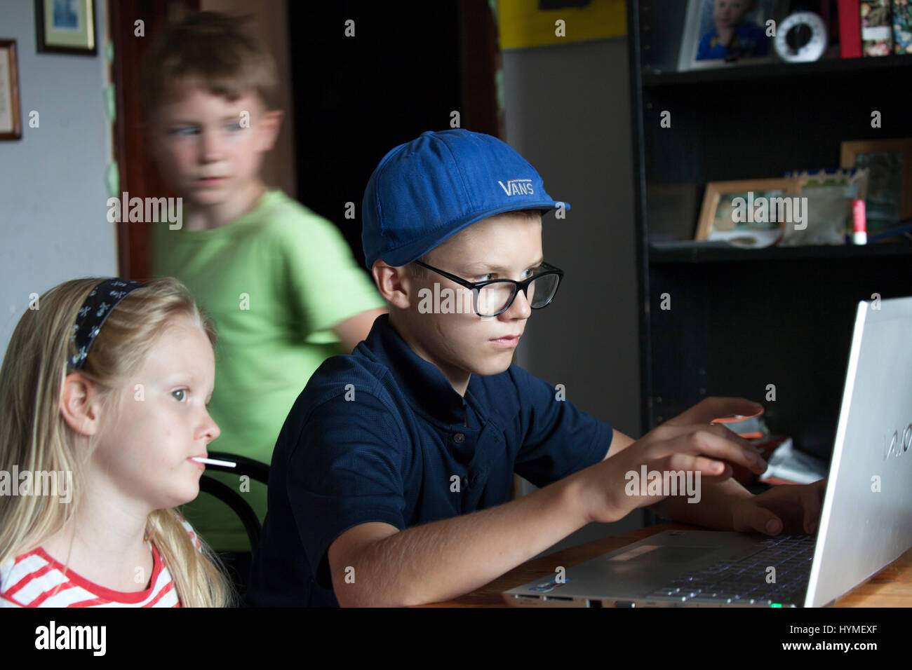 Les enfants travaillant sur le téléchargement d'un film sur l'ordinateur. Polish garçons 10 et 12 ans, fille 8. Zawady Europe centrale Pologne Banque D'Images