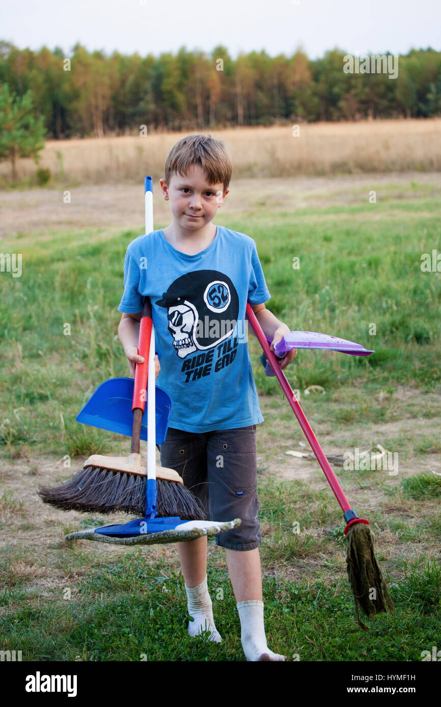 Garçon Polonais travaillant dur 8 ans réunissant les fournitures de nettoyage à l'aide avec un projet familial. Zawady Europe centrale Pologne Banque D'Images