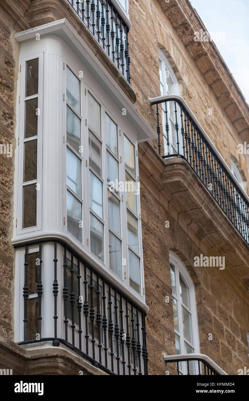 Détail d'un balcon et de grandes fenêtres sur le temps du xixe siècle, rue étroite à l'architecture traditionnelle à Cadix, Espagne Banque D'Images