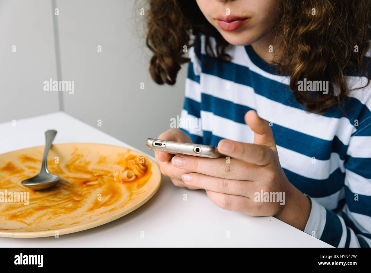 Girl watching her smartphone assis à la table Banque D'Images