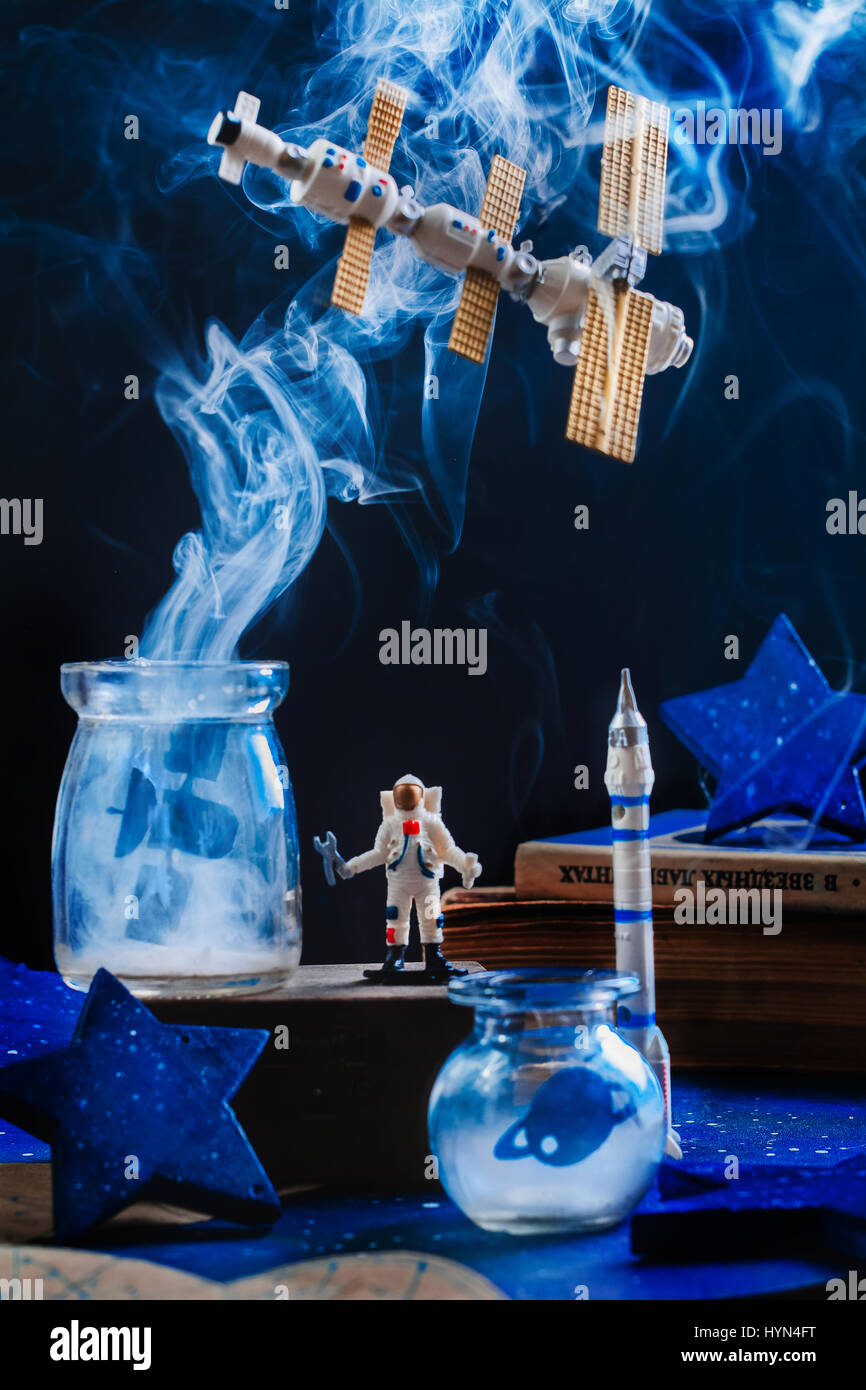 Toy station spatiale avec la fumée et de l'astronaute sur fond sombre Banque D'Images