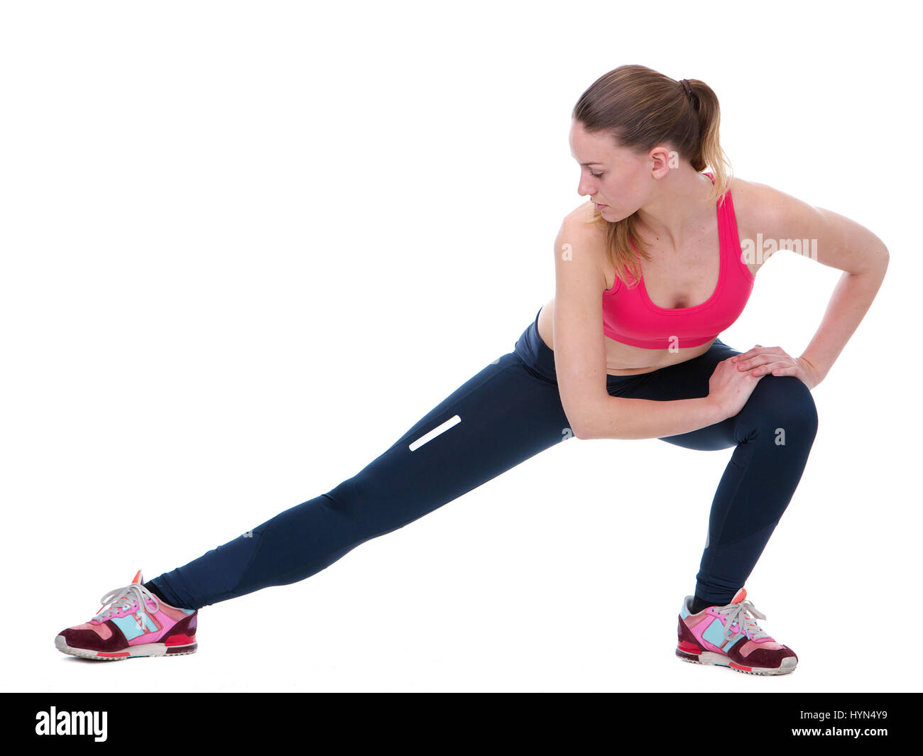 Portrait horizontal d'une jeune femme l'étirement des muscles des jambes isolées sur fond blanc Banque D'Images
