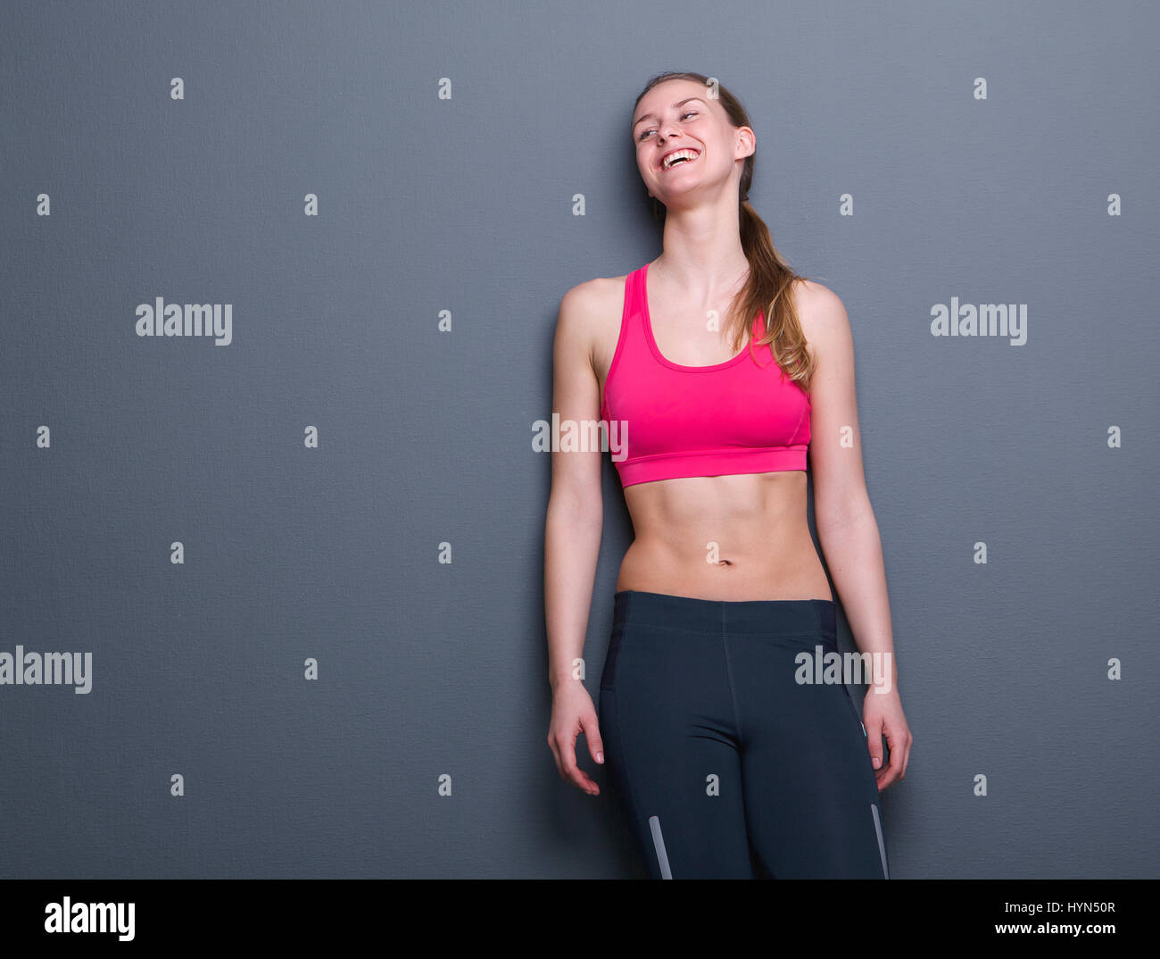 Portrait d'une jeune femme en vêtements de sport debout sur fond gris Banque D'Images