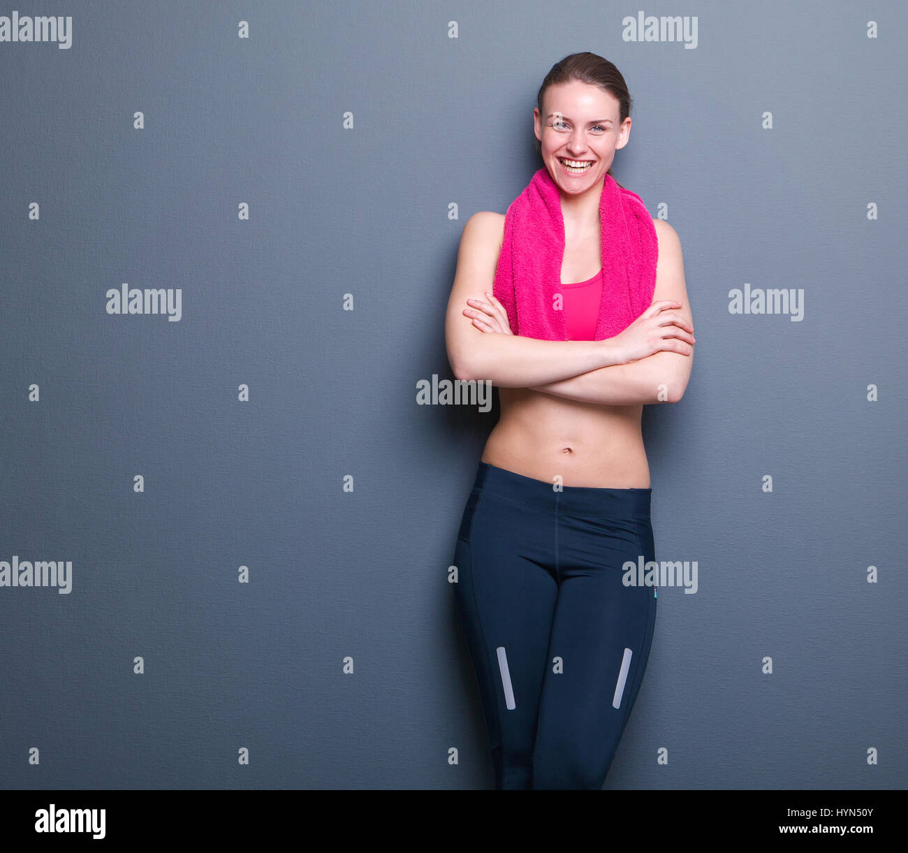 Portrait of a smiling young woman relaxing athlétique sur fond gris avec serviette Banque D'Images