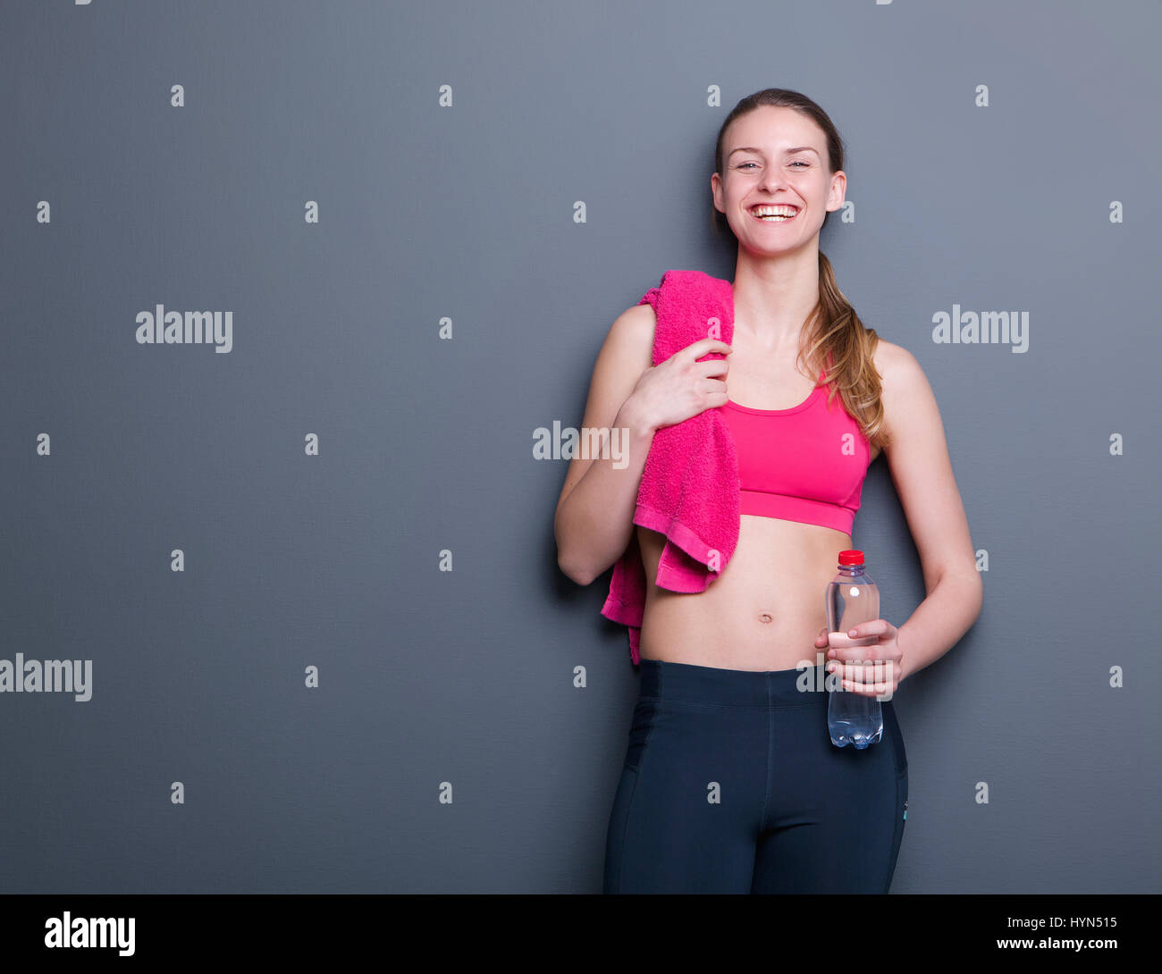 Portrait of a young woman smiling avec serviette et une bouteille d'eau après entraînement Banque D'Images