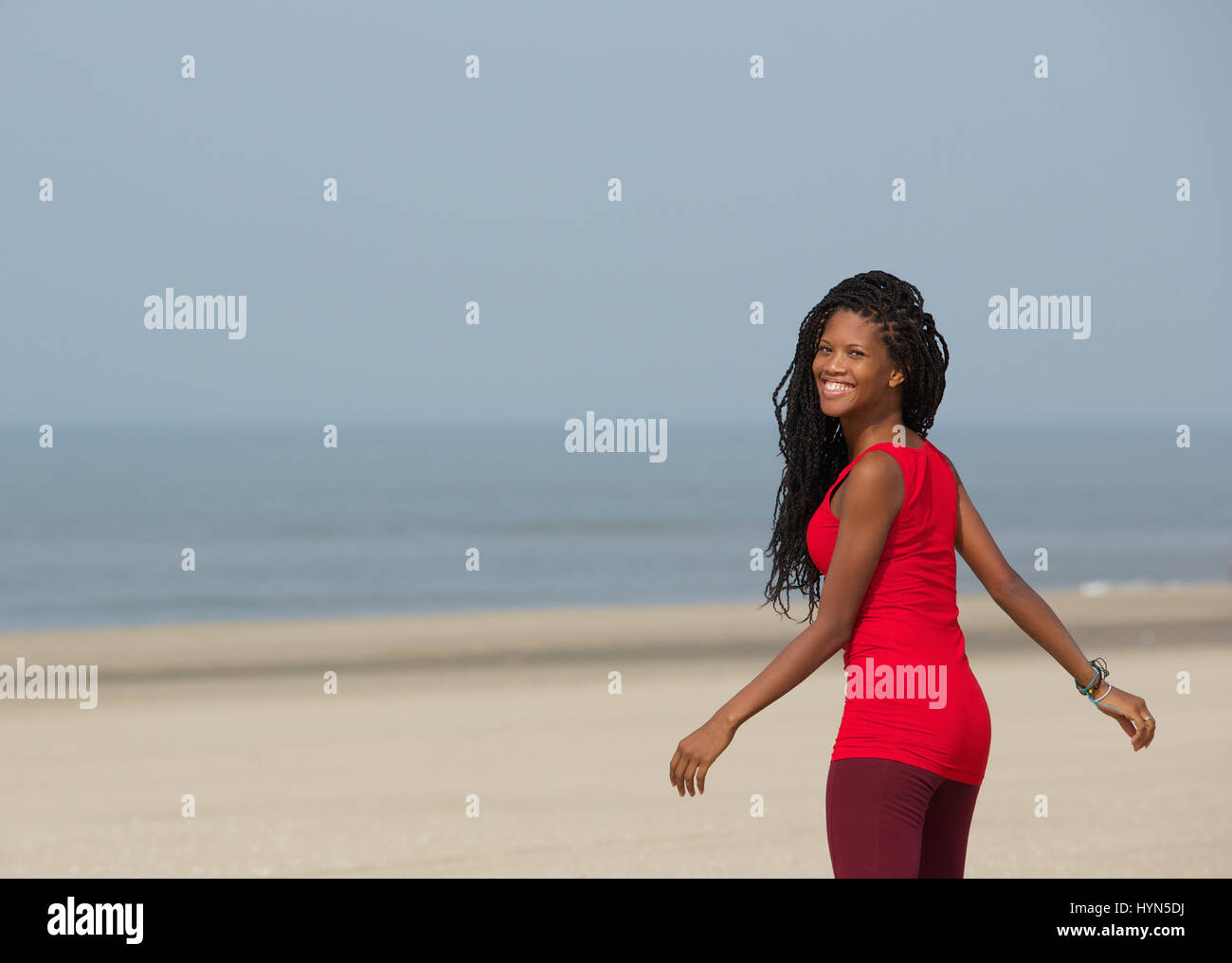 Portrait of a smiling african american woman walking at the beach Banque D'Images