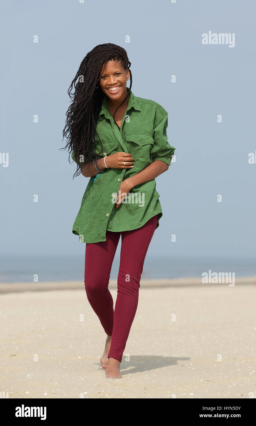 Portrait of a happy african american woman walking on the beach Banque D'Images