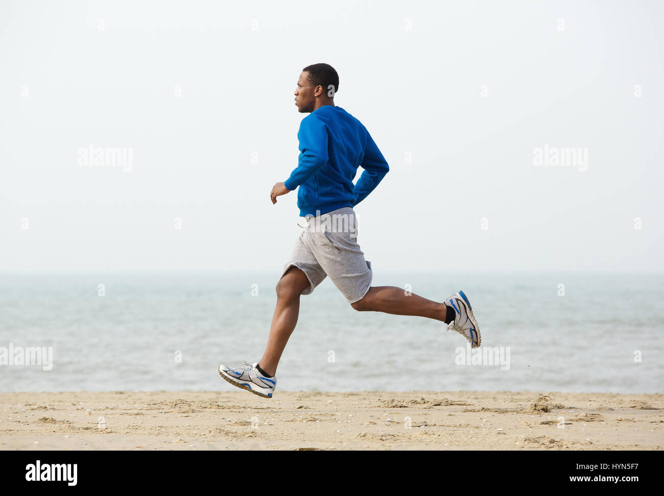 Jeune homme noir en bonne santé le jogging sur la plage Banque D'Images