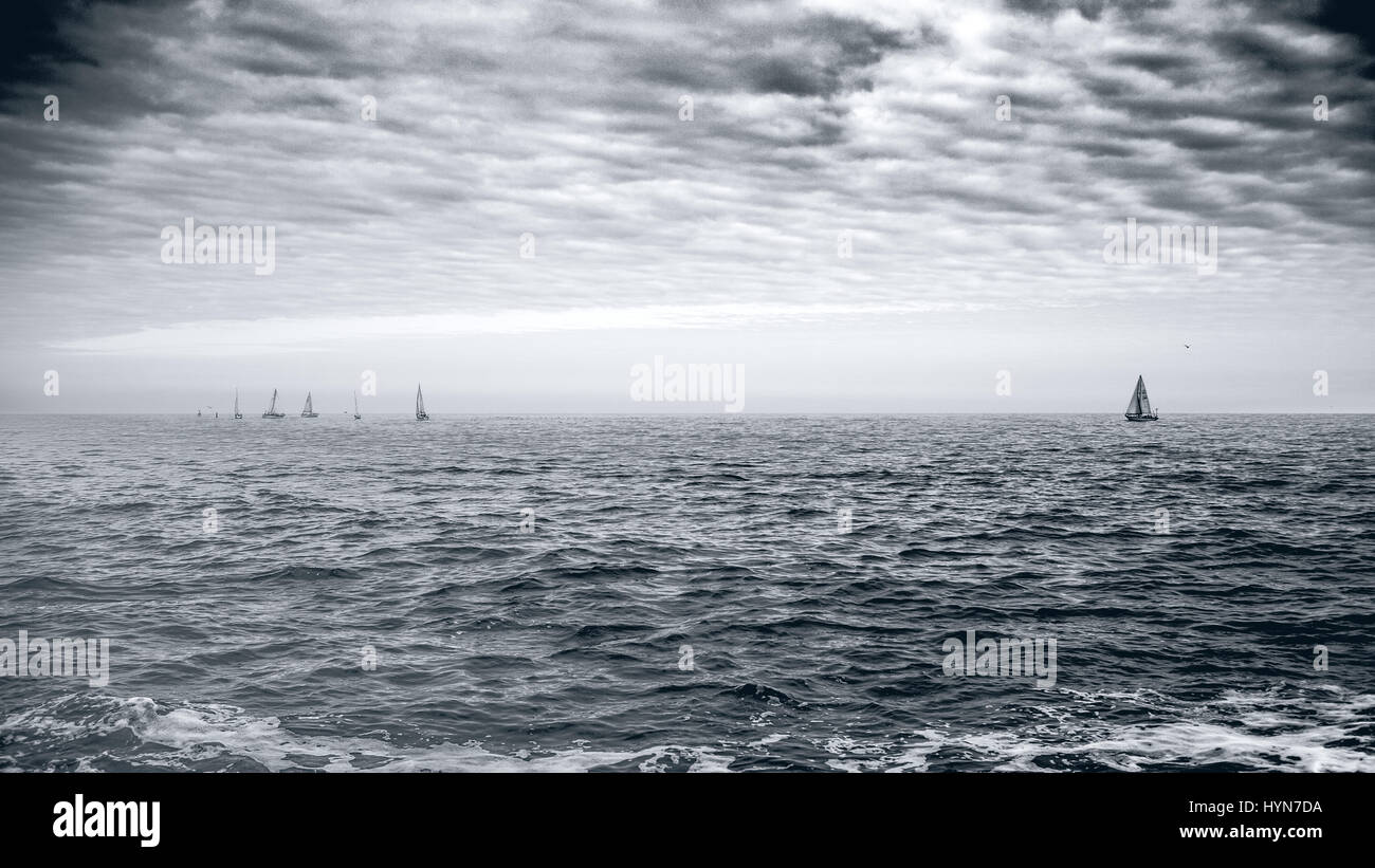 Yacht à voile course régate sur l'eau de la mer d'Irlande sur un jour nuageux. Photographie noir et blanc. Banque D'Images