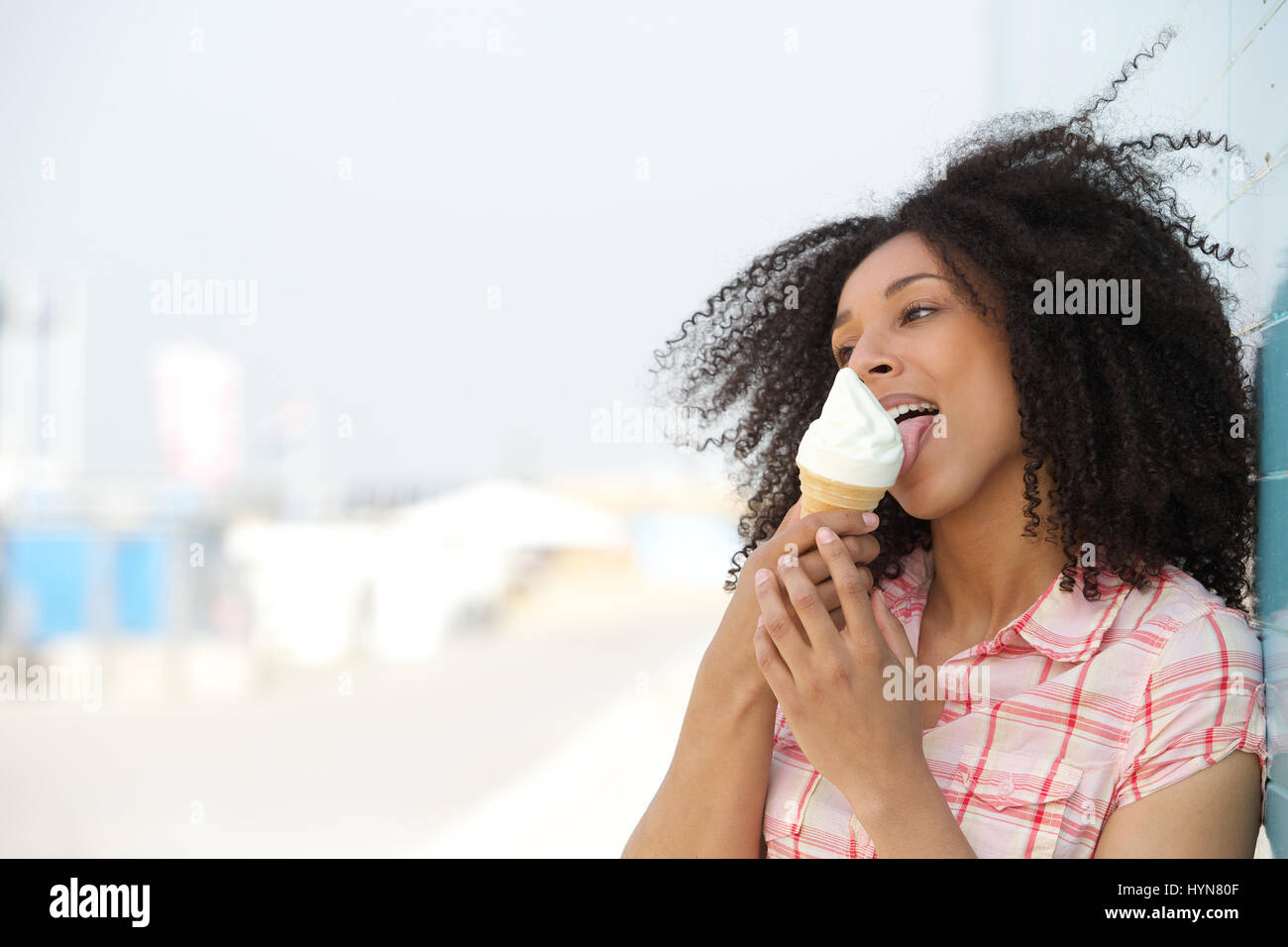 Portrait d'une jeune femme lui lécher la crème glacée en plein air en été Banque D'Images