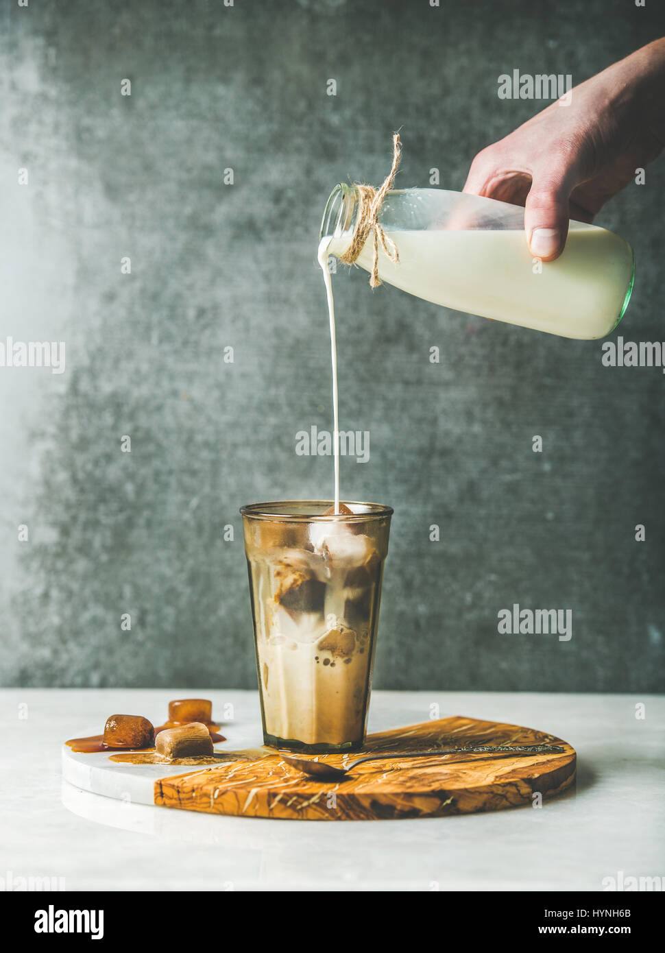 La main de l'homme de verser le lait au caramel latte glacé cocktail café Banque D'Images