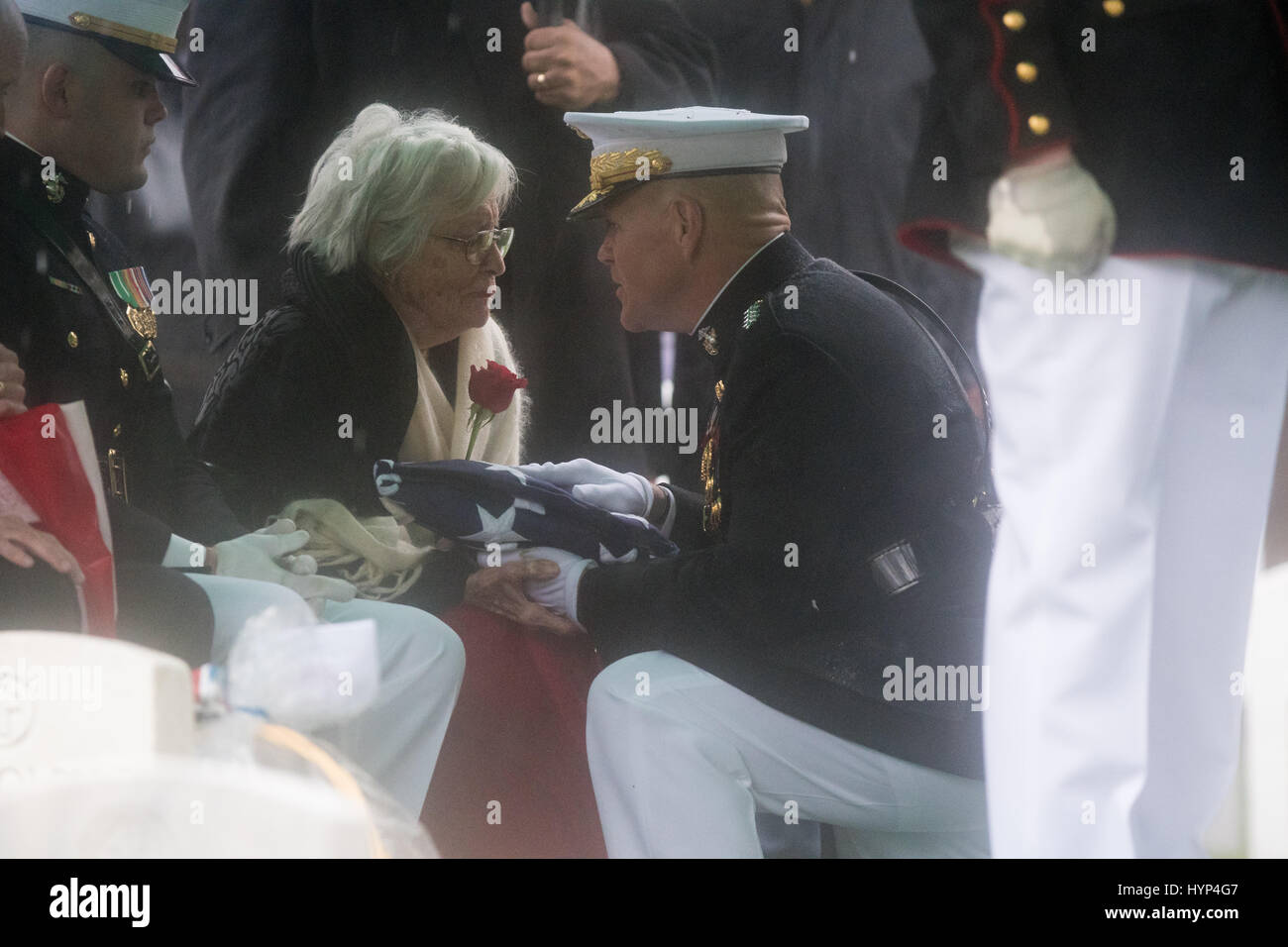 Arlington, États-Unis d'Amérique. 06 avr, 2017. Commandant de la Marine Corps le général Robert Neller, droite, le remet à Anne Glenn, veuve de John Glenn, au cours de la service de la section 35 du Cimetière National d'Arlington, le 6 avril 2017 à Arlington, en Virginie. Glenn, le premier astronaute américain en orbite autour de la Terre et plus tard un sénateur des Etats-Unis, est décédé à l'âge de 95 ans le 8 décembre 2016. Credit : Planetpix/Alamy Live News Banque D'Images