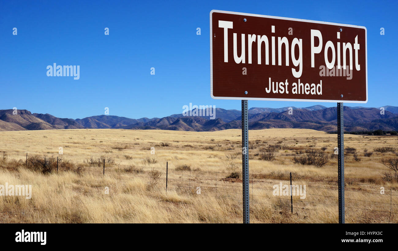 Tournant juste avant brown road sign avec ciel bleu et désert Banque D'Images