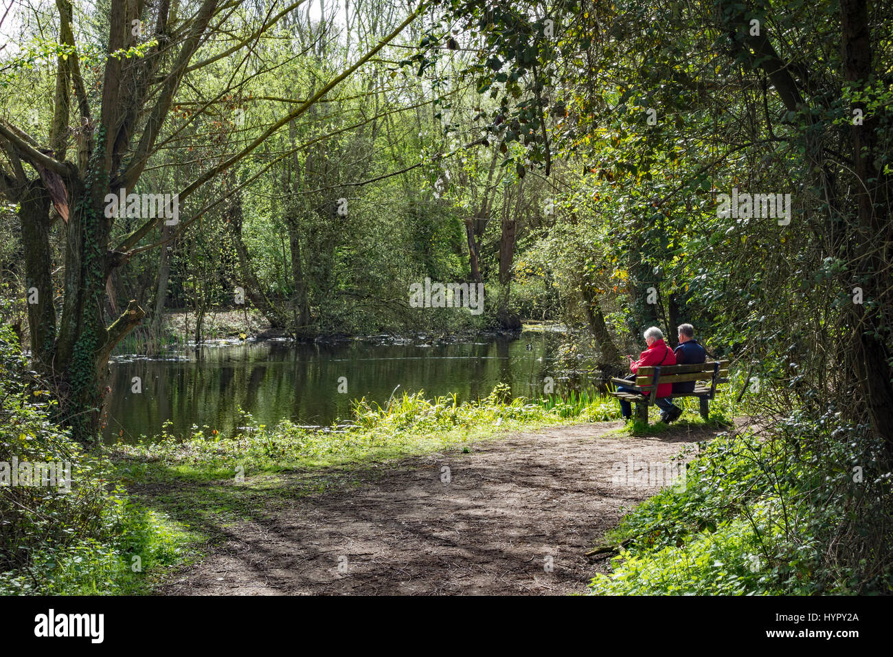 Vieux couple assis sur un banc au bord du lac de profiter du soleil de printemps Banque D'Images