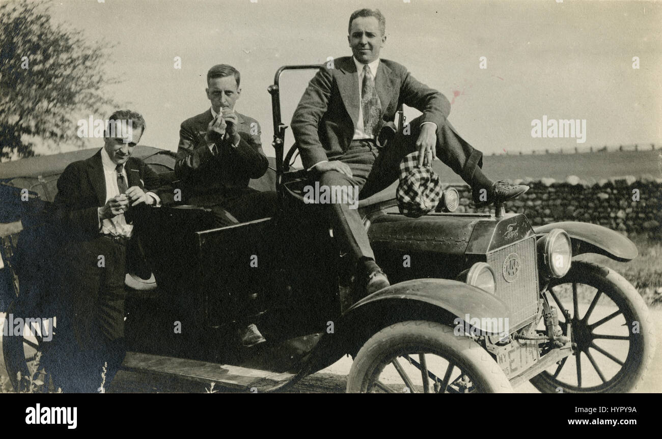 Meubles anciens 1915 photographie, trois hommes sur un roadster Ford automobile. L'immatriculation est de New York en 1915. Il y a un badge AAA sur la grille. Un homme est allumer une cigarette. SOURCE : tirage photographique original. Banque D'Images