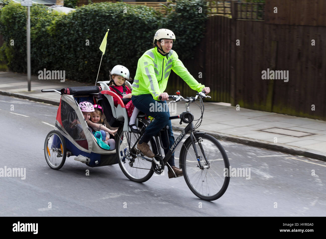 Cycliste femme sur Vélo / Vélo avec  + 3 enfants ; coopération avec siège enfant pilote casque & cycle remorquage remorque Chariot avec 2 / 2 enfants avec un casque. UK. Banque D'Images