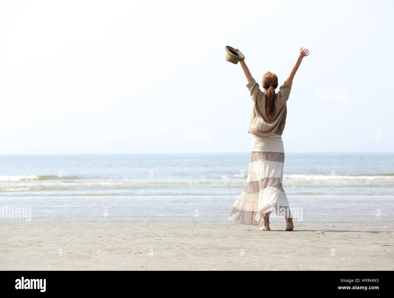 Femme aux bras levés à la célébration de l'arrière plage Banque D'Images