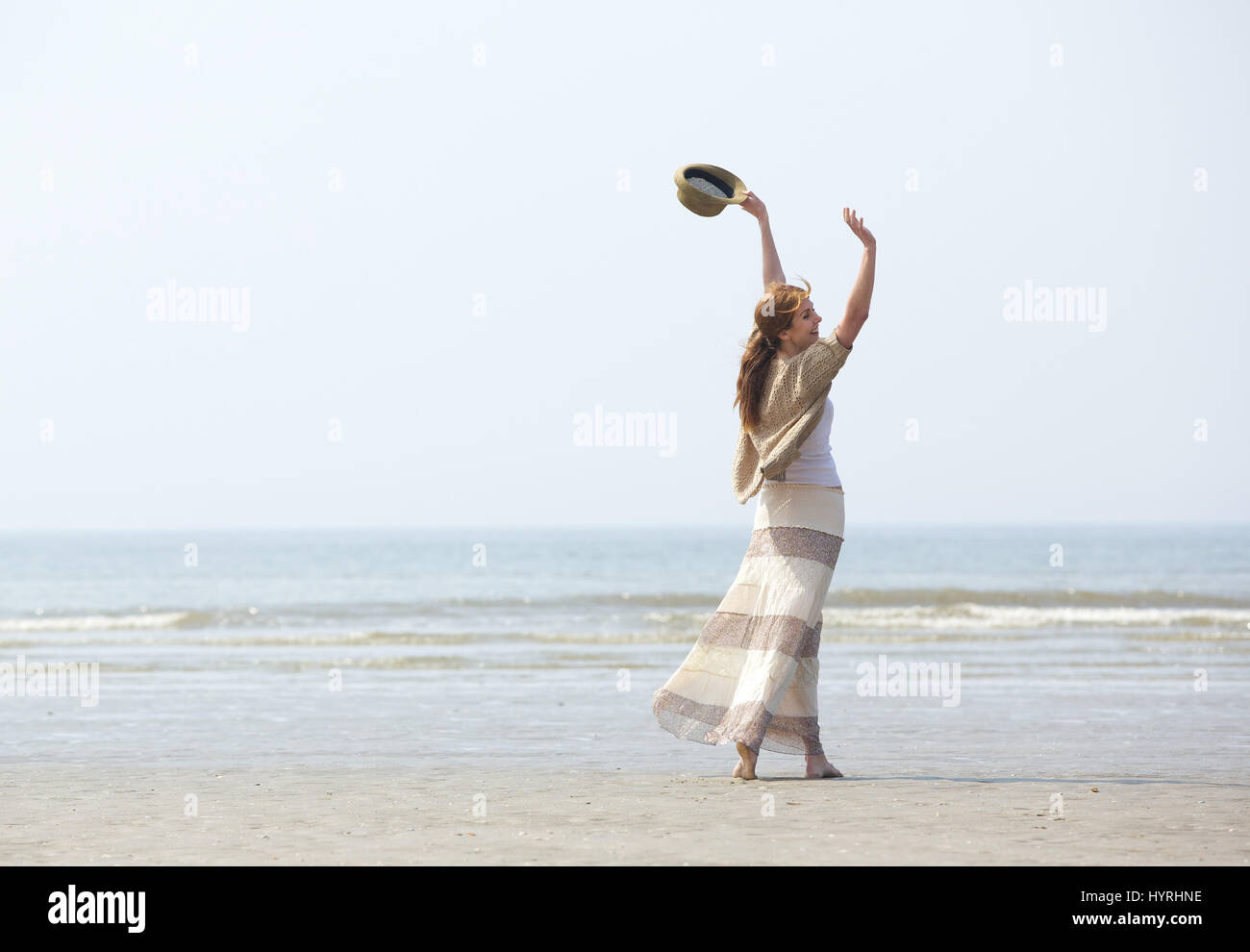 Portrait d'une femme marchant sur la plage avec les bras levés dans la célébration Banque D'Images