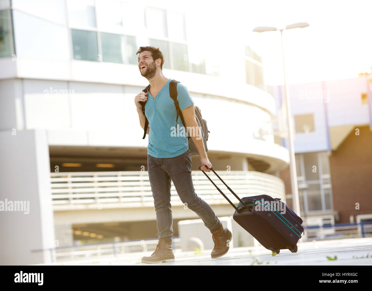 Portrait d'un homme moderne smiling outdoors avec valise et sac Banque D'Images