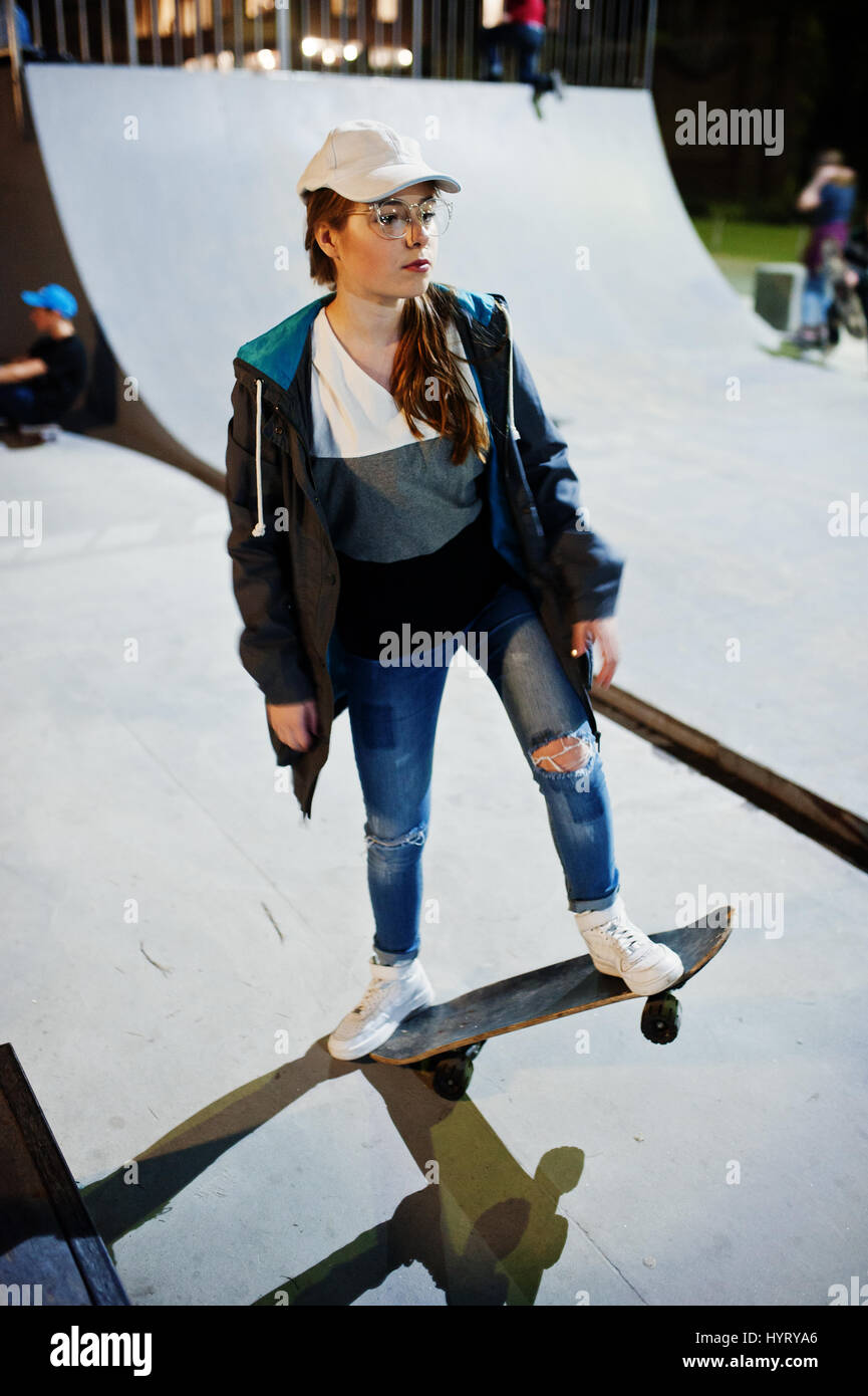 Jeune fille de la ville d'adolescent avec skateboard, l'usure sur les  lunettes, le chapeau et jeans déchirés à skate park le soir Photo Stock -  Alamy