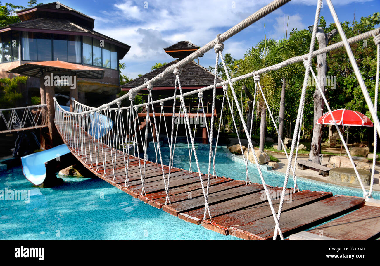 Petit pont suspendu à la corde de l'autre côté de la piscine dans le parc libre pour les personnes en photo extérieure bien l'éclairage. Banque D'Images